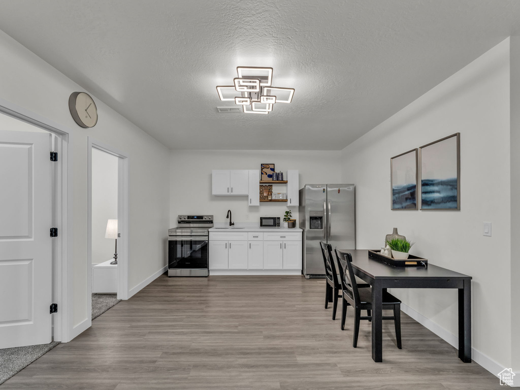Dining area featuring light wood finished floors, baseboards, and a textured ceiling