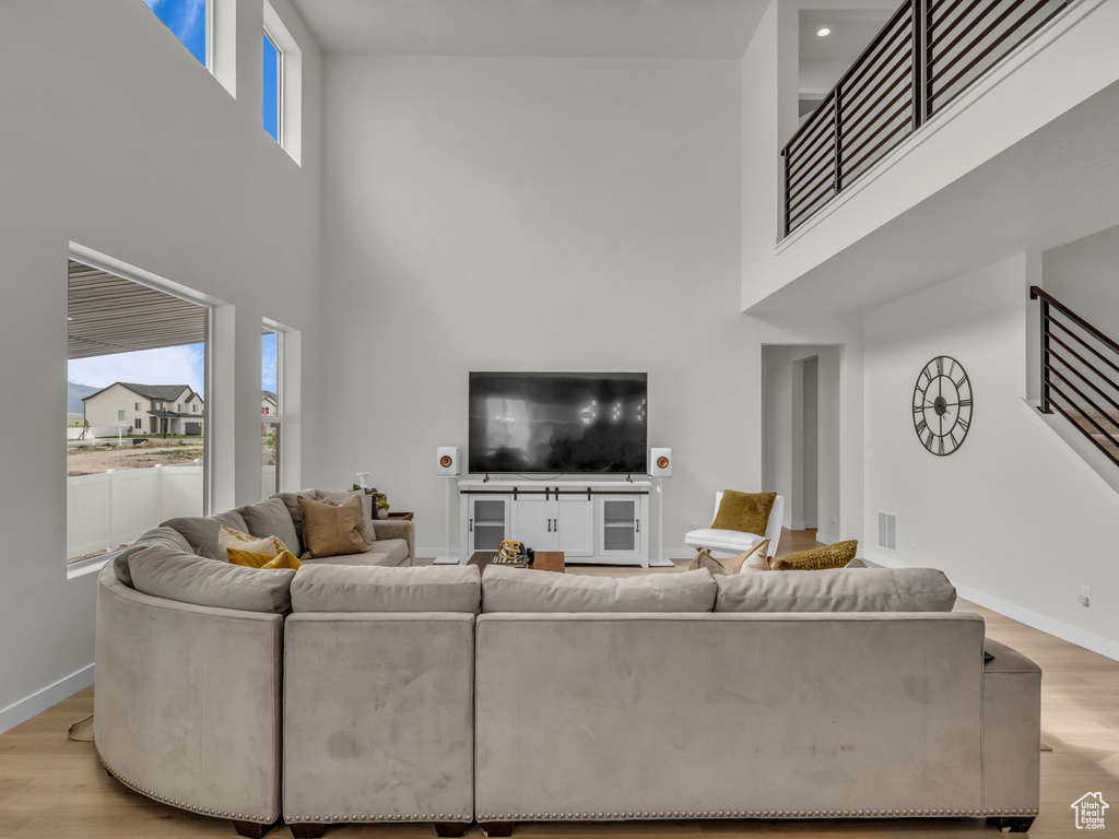 Living room with a high ceiling, wood finished floors, and baseboards