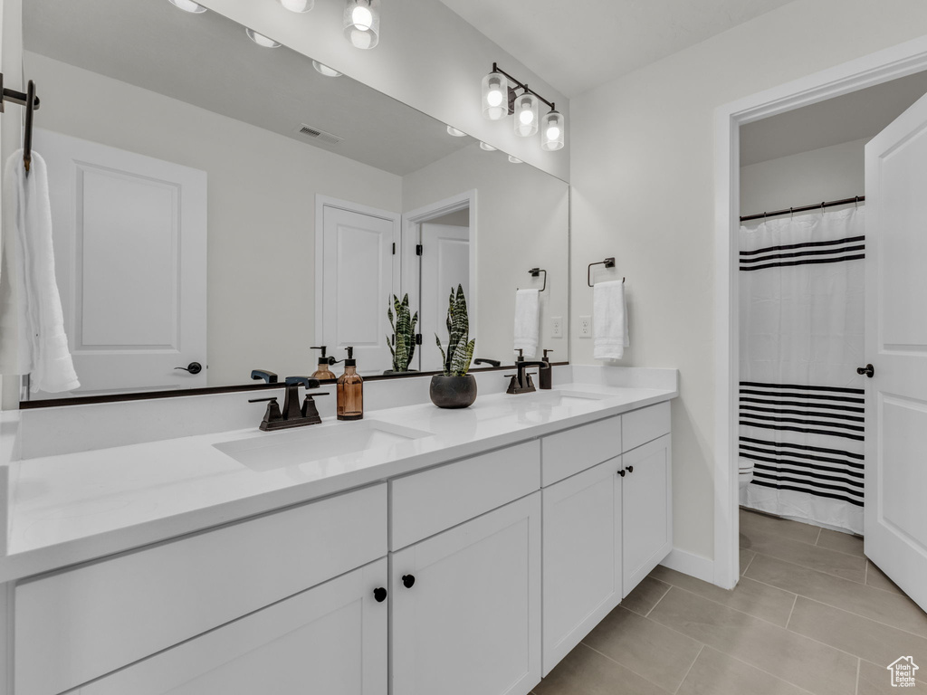 Bathroom featuring double vanity, tile patterned flooring, and baseboards