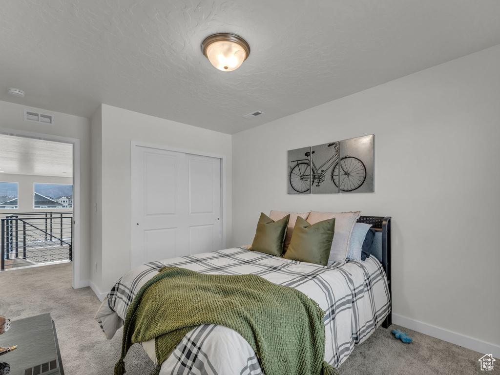 Bedroom with light carpet, baseboards, and a closet
