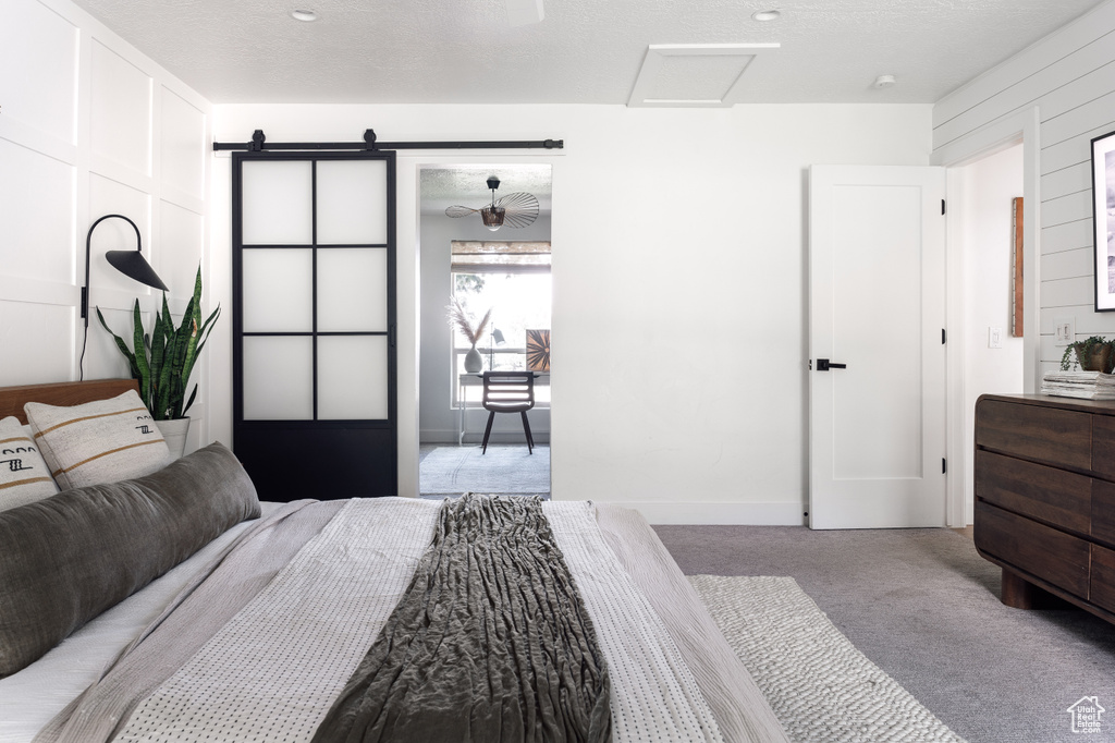 Bedroom featuring attic access, carpet flooring, baseboards, and a barn door