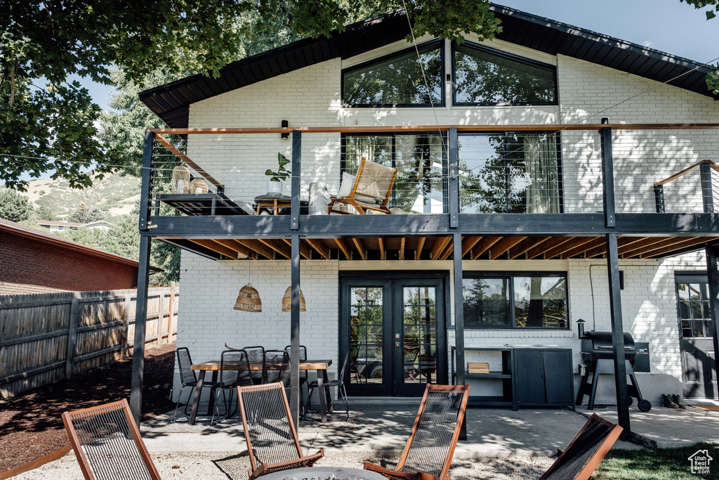 Rear view of property with french doors, brick siding, a balcony, and a patio area