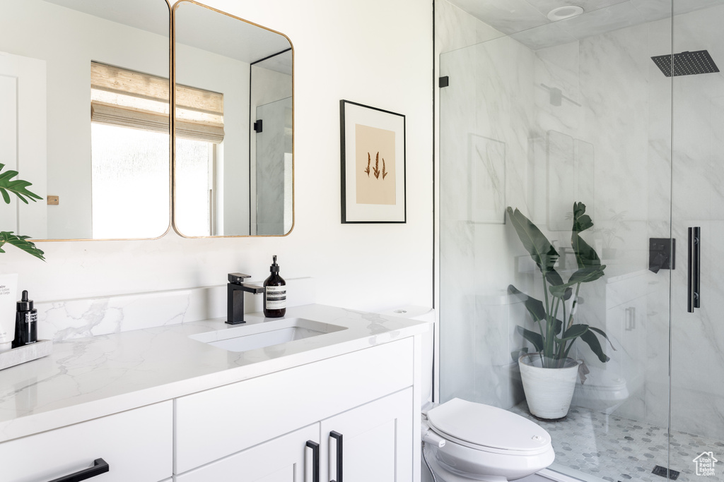 Full bathroom with vanity, toilet, and a marble finish shower