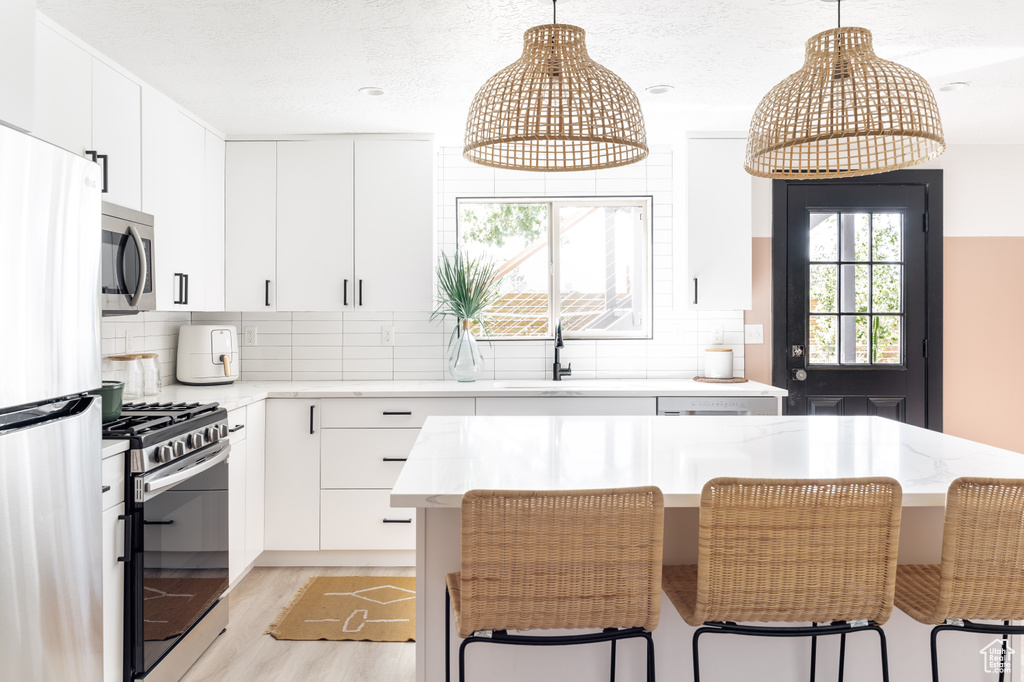 Kitchen featuring stainless steel appliances, a sink, pendant lighting, and a kitchen breakfast bar