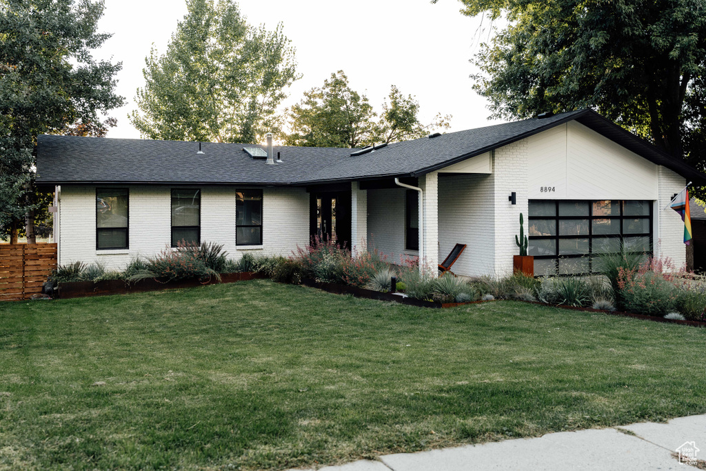 View of front of property with brick siding, an attached garage, a front yard, and a shingled roof