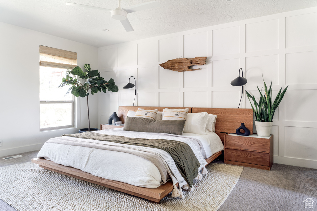 Bedroom with light carpet, a decorative wall, and ceiling fan