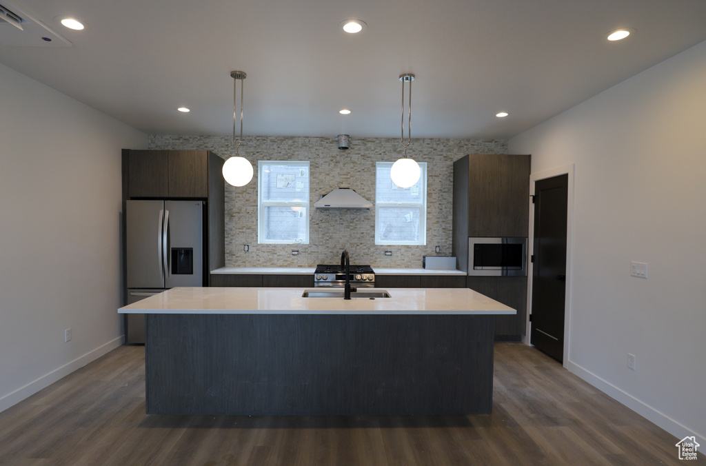 Kitchen with a sink, appliances with stainless steel finishes, light countertops, dark wood finished floors, and recessed lighting
