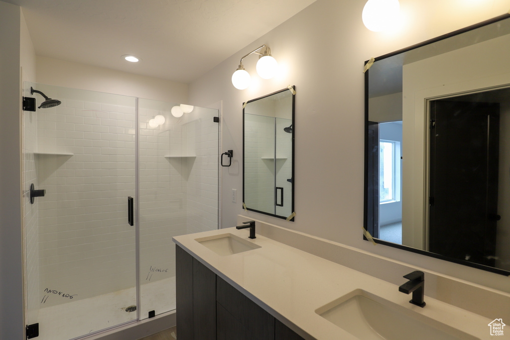 Full bath featuring a shower stall, double vanity, and recessed lighting