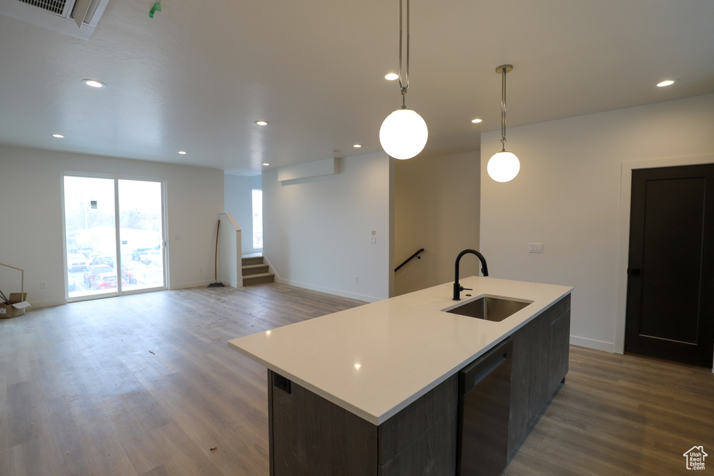 Kitchen featuring a sink, wood finished floors, light countertops, and recessed lighting