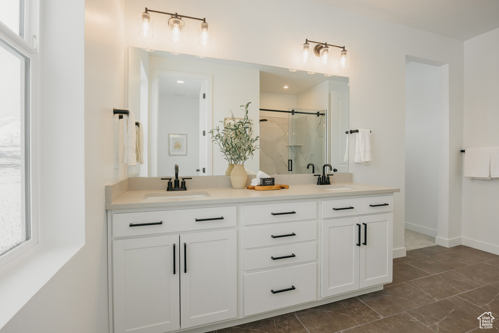 Full bath featuring double vanity, a shower stall, healthy amount of natural light, and marble finish floors