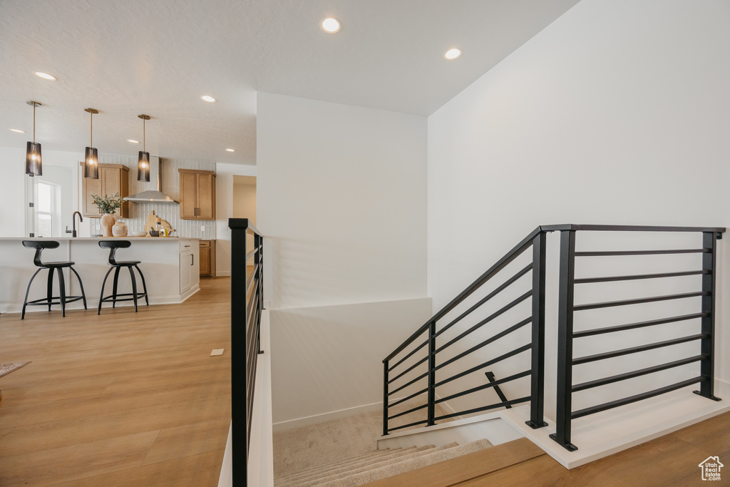 Staircase with wood finished floors and recessed lighting