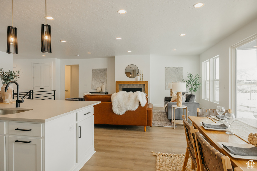 Kitchen featuring a sink, recessed lighting, light wood finished floors, white cabinetry, and light countertops