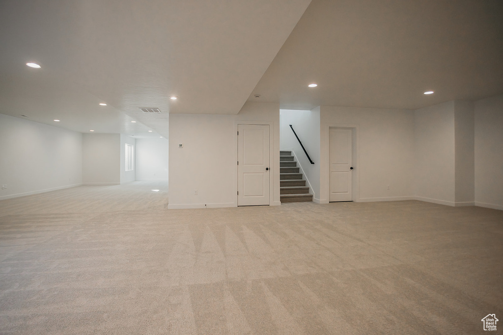 Finished below grade area with stairway, recessed lighting, light carpet, and baseboards