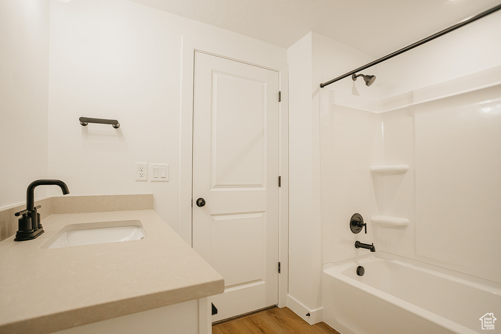 Bathroom with shower / washtub combination, wood finished floors, and vanity
