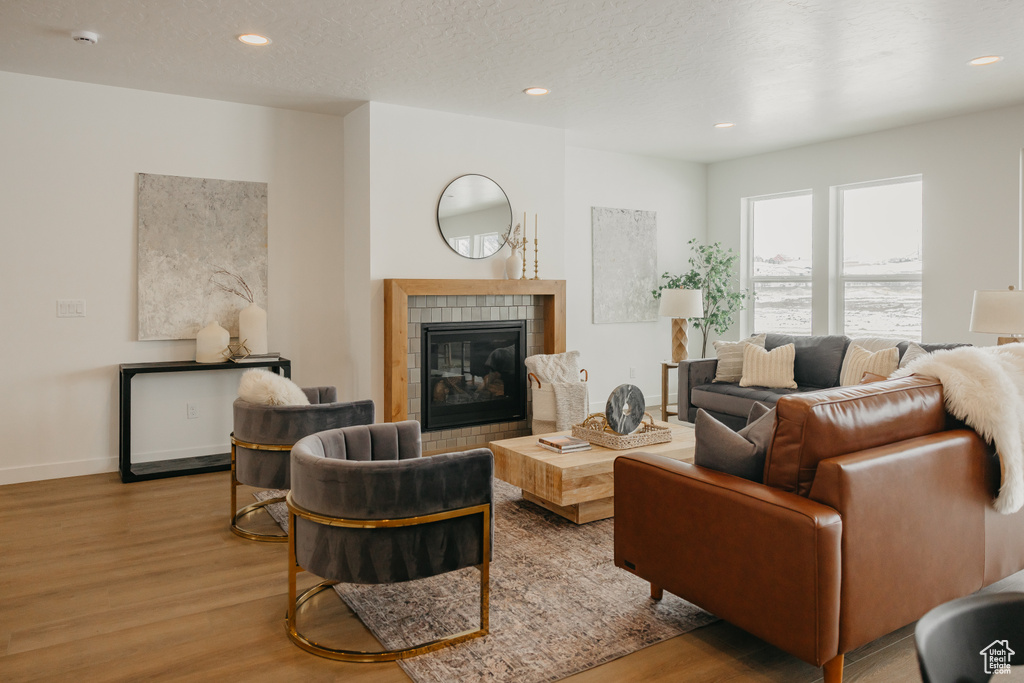 Living room with wood finished floors, a fireplace, recessed lighting, and baseboards