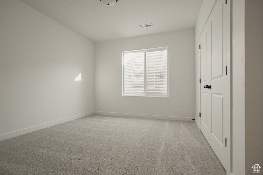 Unfurnished room featuring baseboards and light carpet