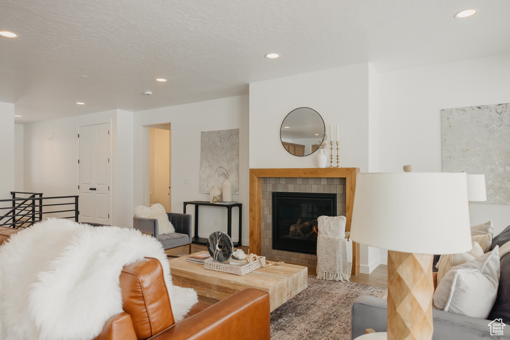 Living area with recessed lighting, a tile fireplace, and wood finished floors