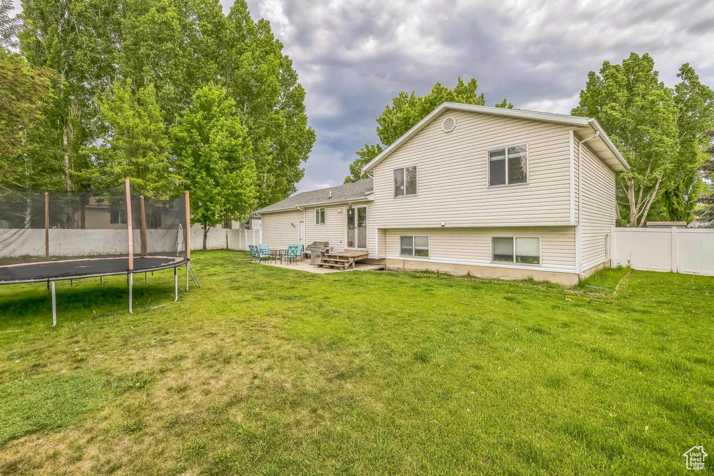 Back of property with a trampoline and a patio
