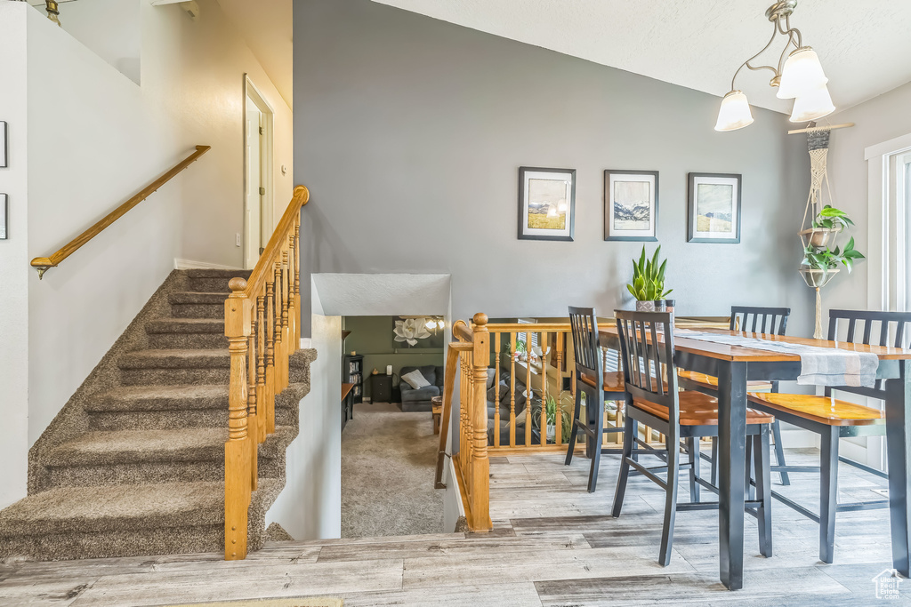 Dining area featuring wood finished floors, vaulted ceiling, and stairway