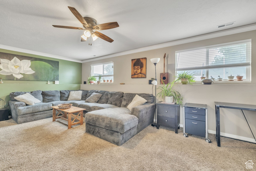 Living area featuring light colored carpet, ceiling fan, crown molding, and baseboards