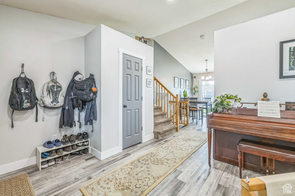 Entrance foyer featuring light wood-type flooring, baseboards, lofted ceiling, stairway, and a chandelier