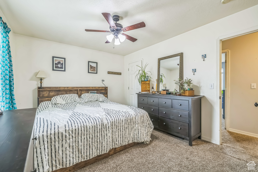 Carpeted bedroom with a ceiling fan and baseboards