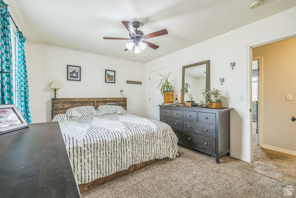 Carpeted bedroom with ceiling fan and baseboards