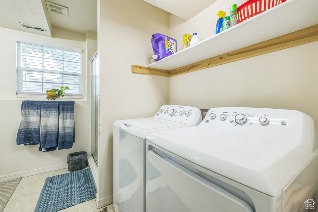 Laundry room with washing machine and clothes dryer, baseboards, and tile patterned flooring