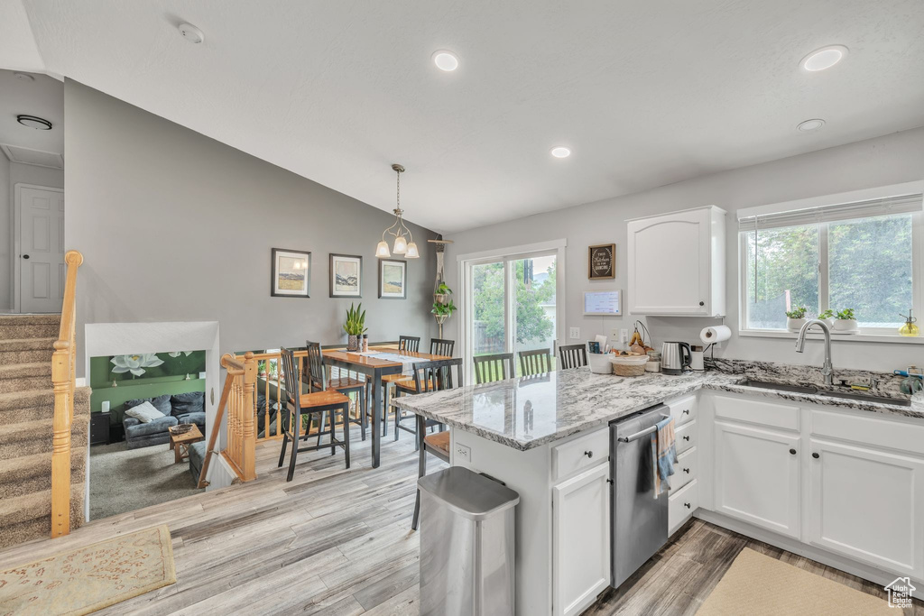 Kitchen featuring dishwasher, a sink, white cabinetry, a peninsula, and light wood-style flooring