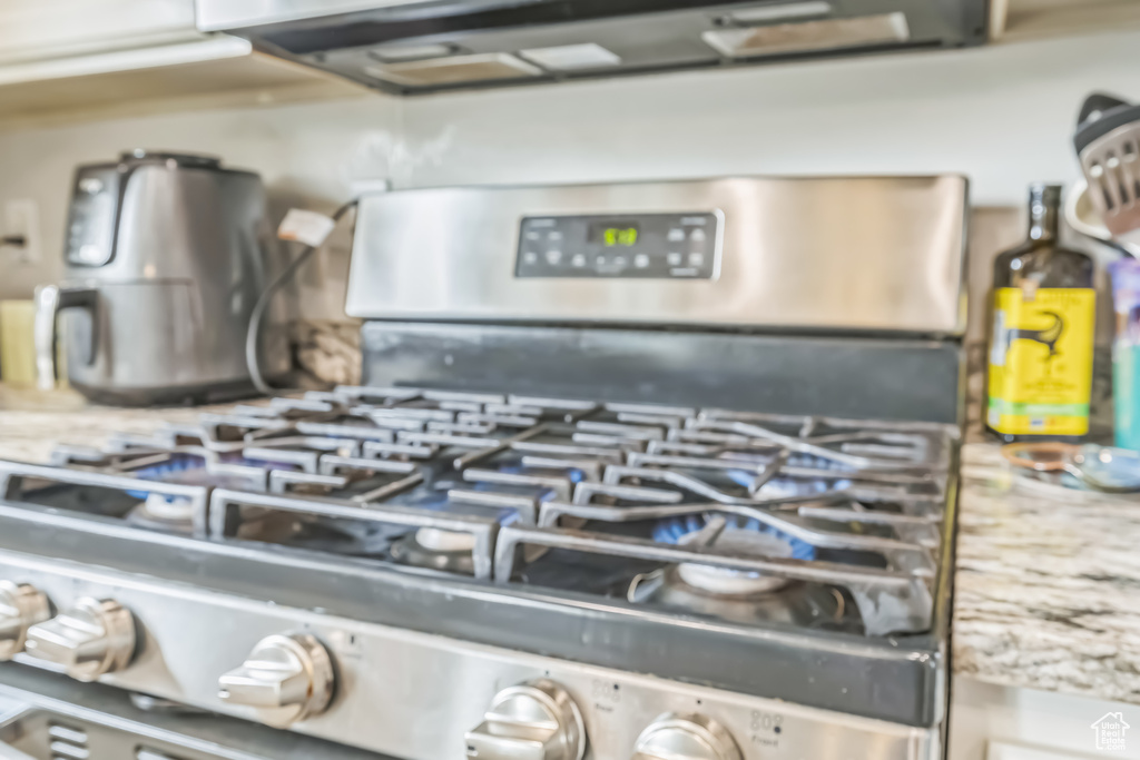 Kitchen view of gas stove, light stone countertops, and decorative backsplash