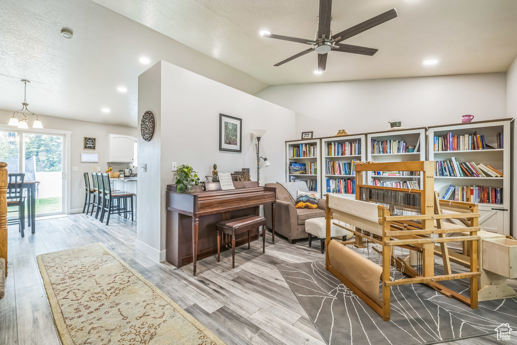 Office space featuring a ceiling fan, lofted ceiling, wood finished floors, and a chandelier