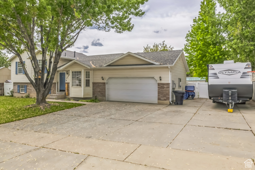 View of front of home with concrete driveway, brick siding, a garage, and roof with shingles
