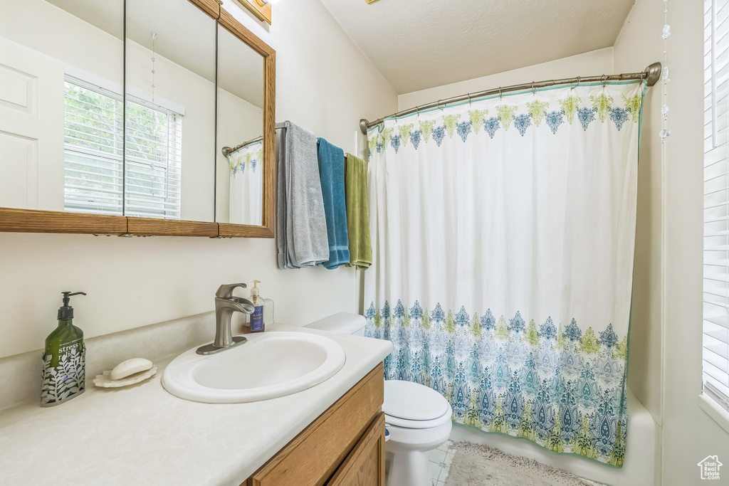 Bathroom with vanity, toilet, and shower / bathtub combination with curtain