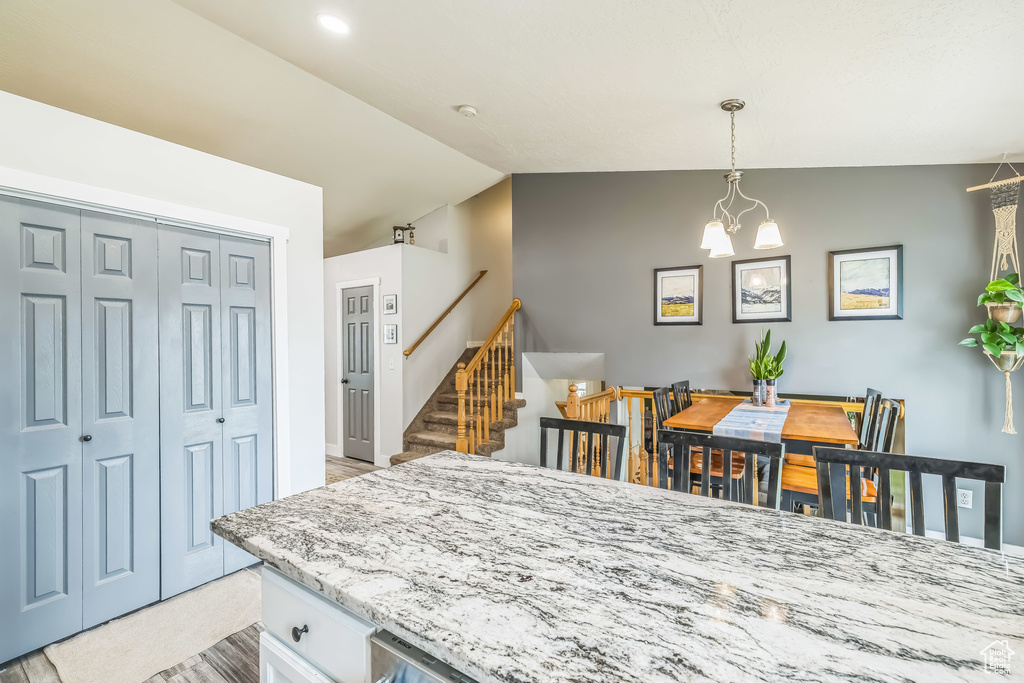 Kitchen with vaulted ceiling, decorative light fixtures, white cabinets, and a chandelier