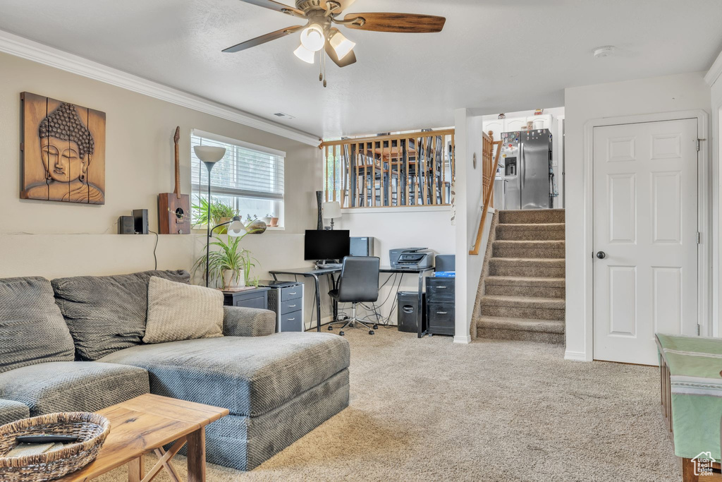 Carpeted living room with ornamental molding, stairway, ceiling fan, and a desk