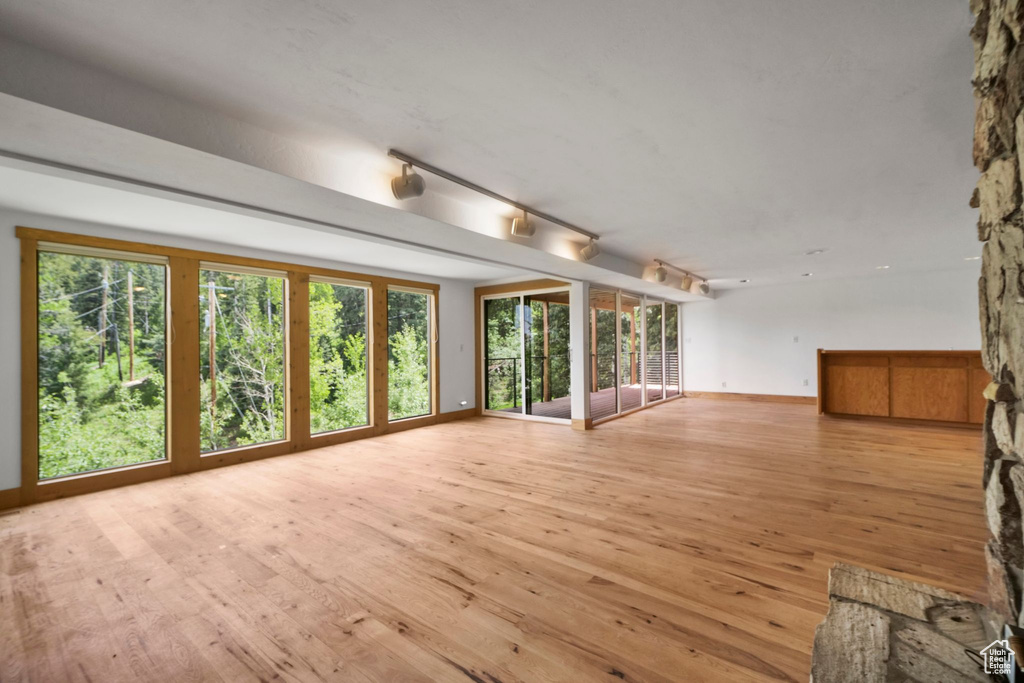 Unfurnished living room with light wood-type flooring, plenty of natural light, and baseboards