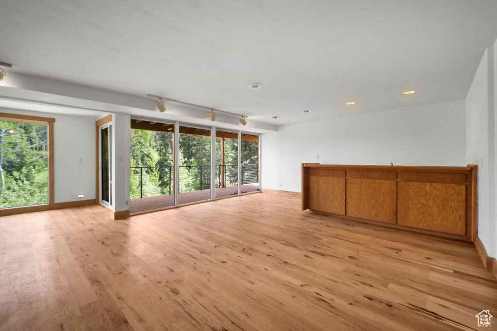 Unfurnished living room featuring light wood-type flooring, plenty of natural light, baseboards, and recessed lighting