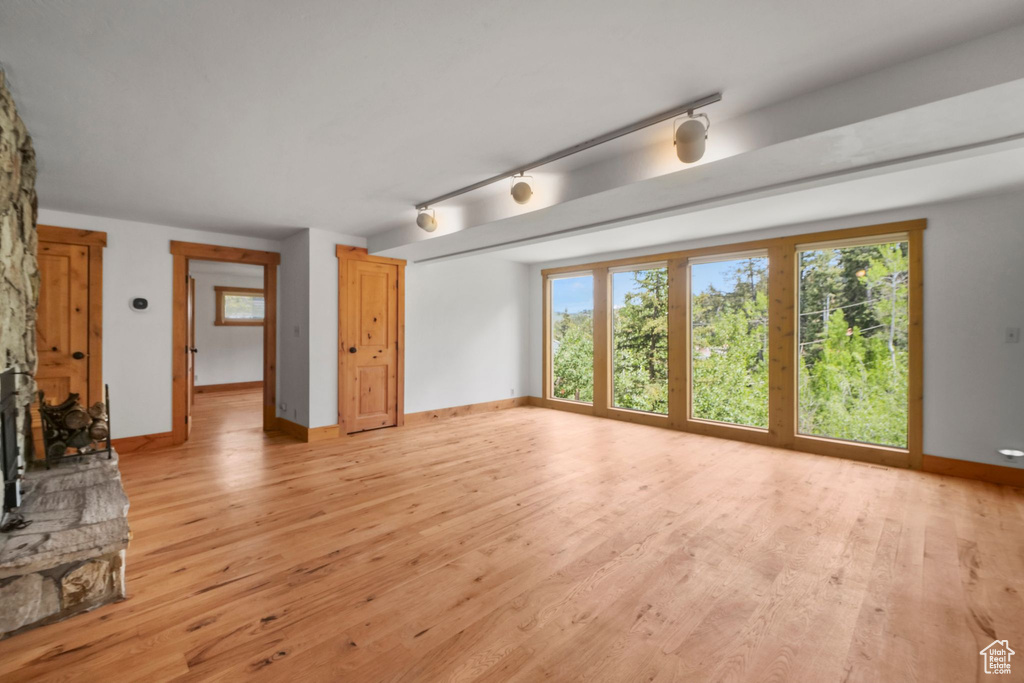 Unfurnished living room featuring light wood-style floors, baseboards, and track lighting