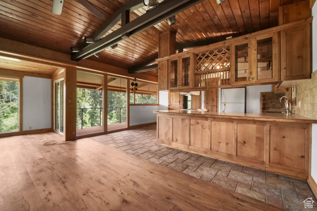 Kitchen featuring freestanding refrigerator, baseboards, glass insert cabinets, a sink, and wood ceiling