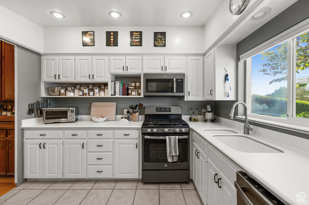 Kitchen featuring appliances with stainless steel finishes, a sink, open shelves, white cabinets, and recessed lighting