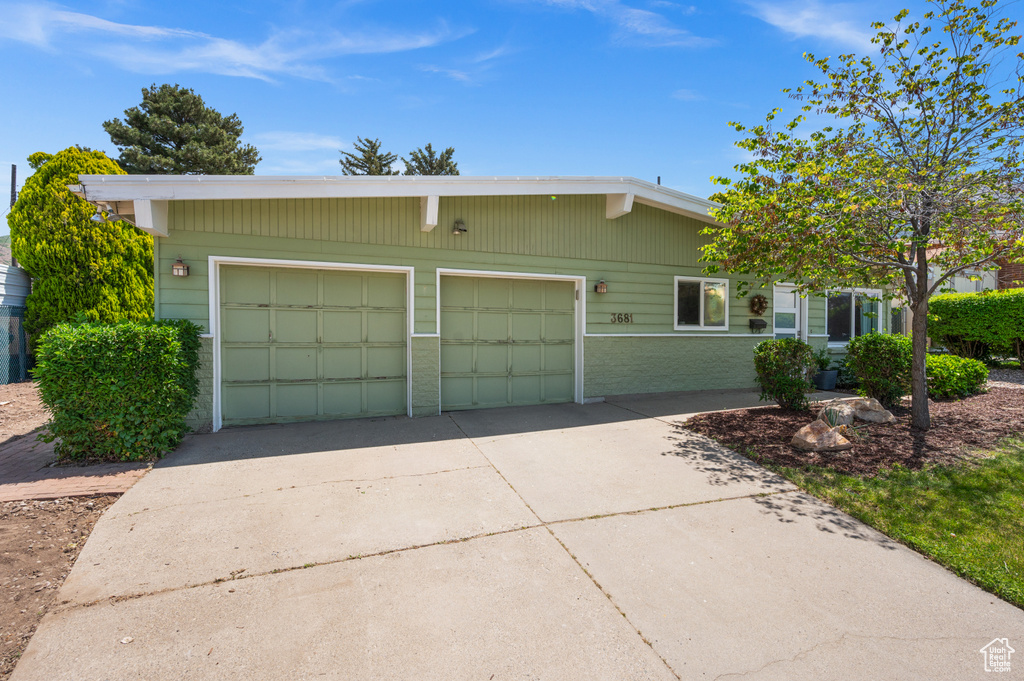 View of front of property with driveway, brick siding, and a garage