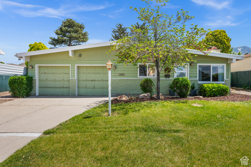 View of front of home with concrete driveway, a front yard, a garage, and brick siding