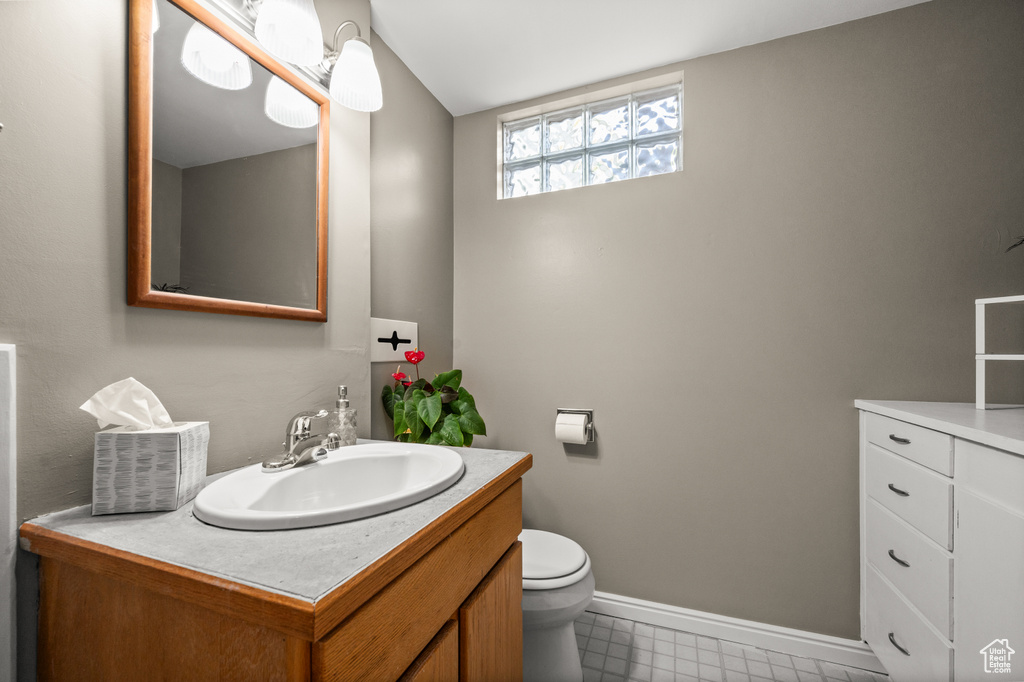 Bathroom with vanity, toilet, baseboards, and tile patterned flooring