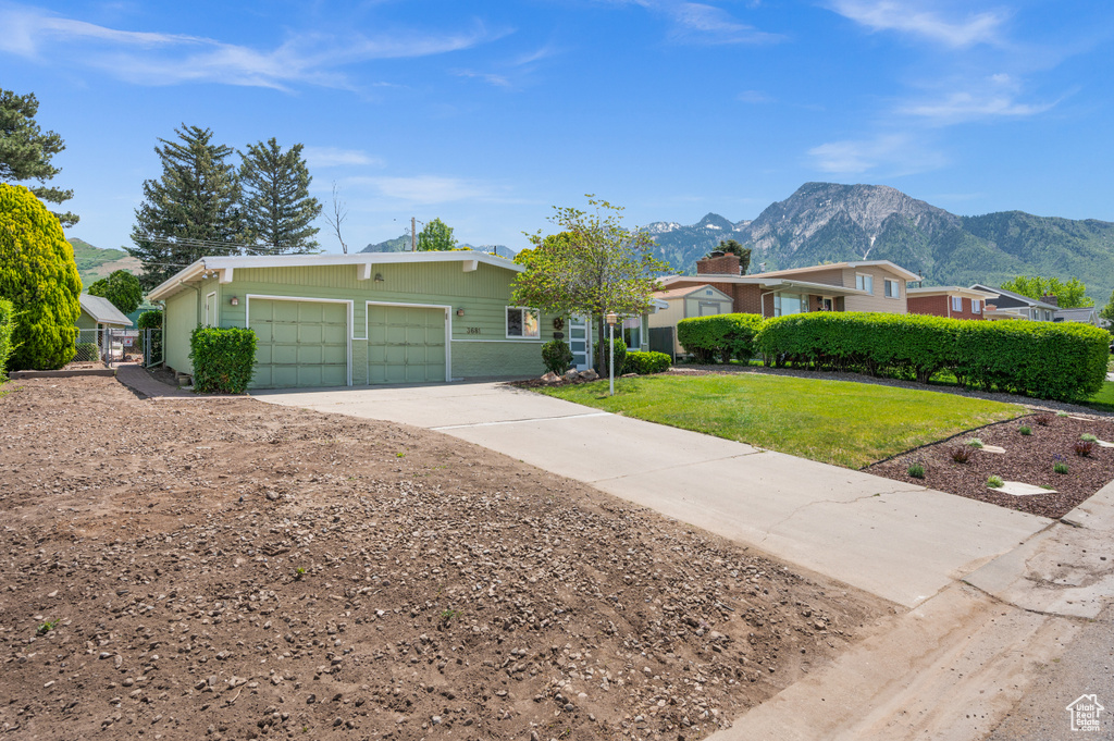 Single story home with a mountain view, a garage, concrete driveway, and a front lawn