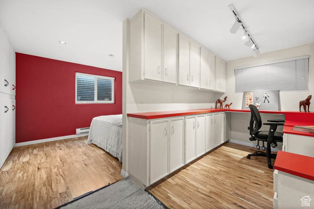 Office space featuring light wood finished floors, a baseboard heating unit, baseboards, and rail lighting