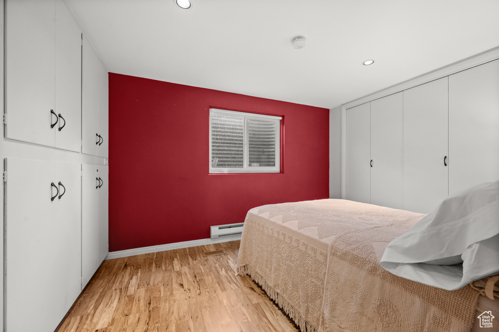 Bedroom featuring baseboard heating, light wood finished floors, baseboards, recessed lighting, and a closet