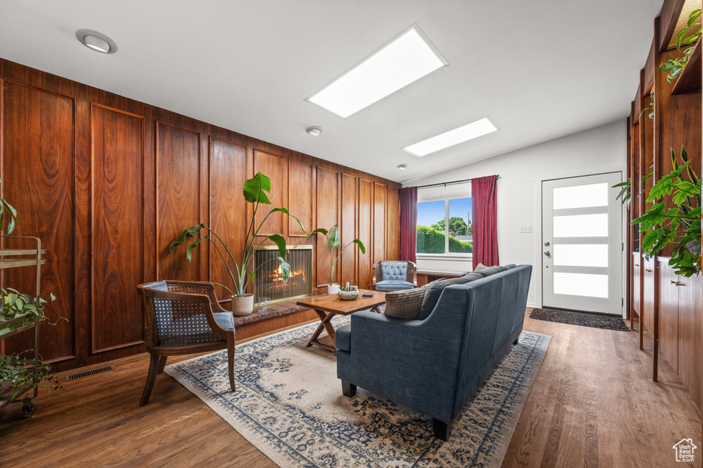 Living room with lofted ceiling, a skylight, and wood finished floors
