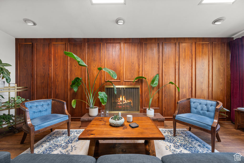 Living room with wood finished floors, a lit fireplace, and wood walls