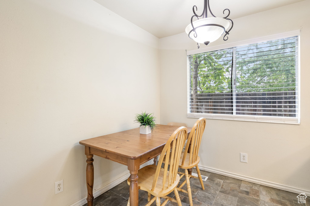 Dining space featuring stone finish flooring, vaulted ceiling, and baseboards