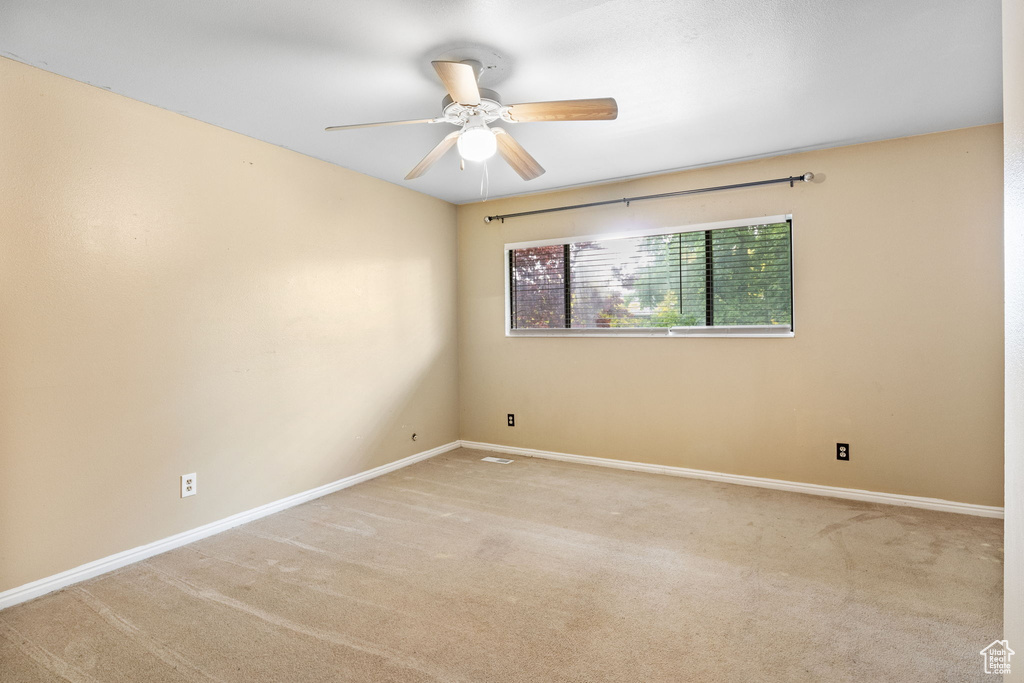 Carpeted spare room with ceiling fan and baseboards